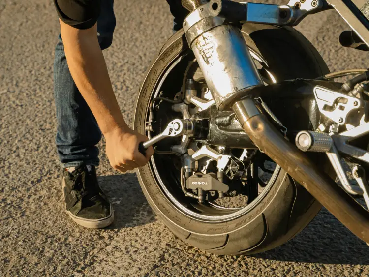 Persona comprobando la presión de un neumático de moto