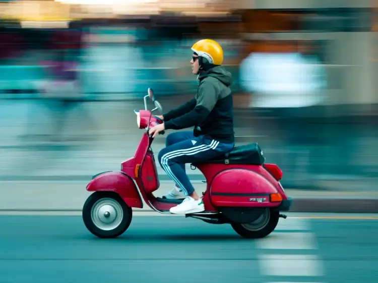 Persona conduciendo una scooter por una ciudad